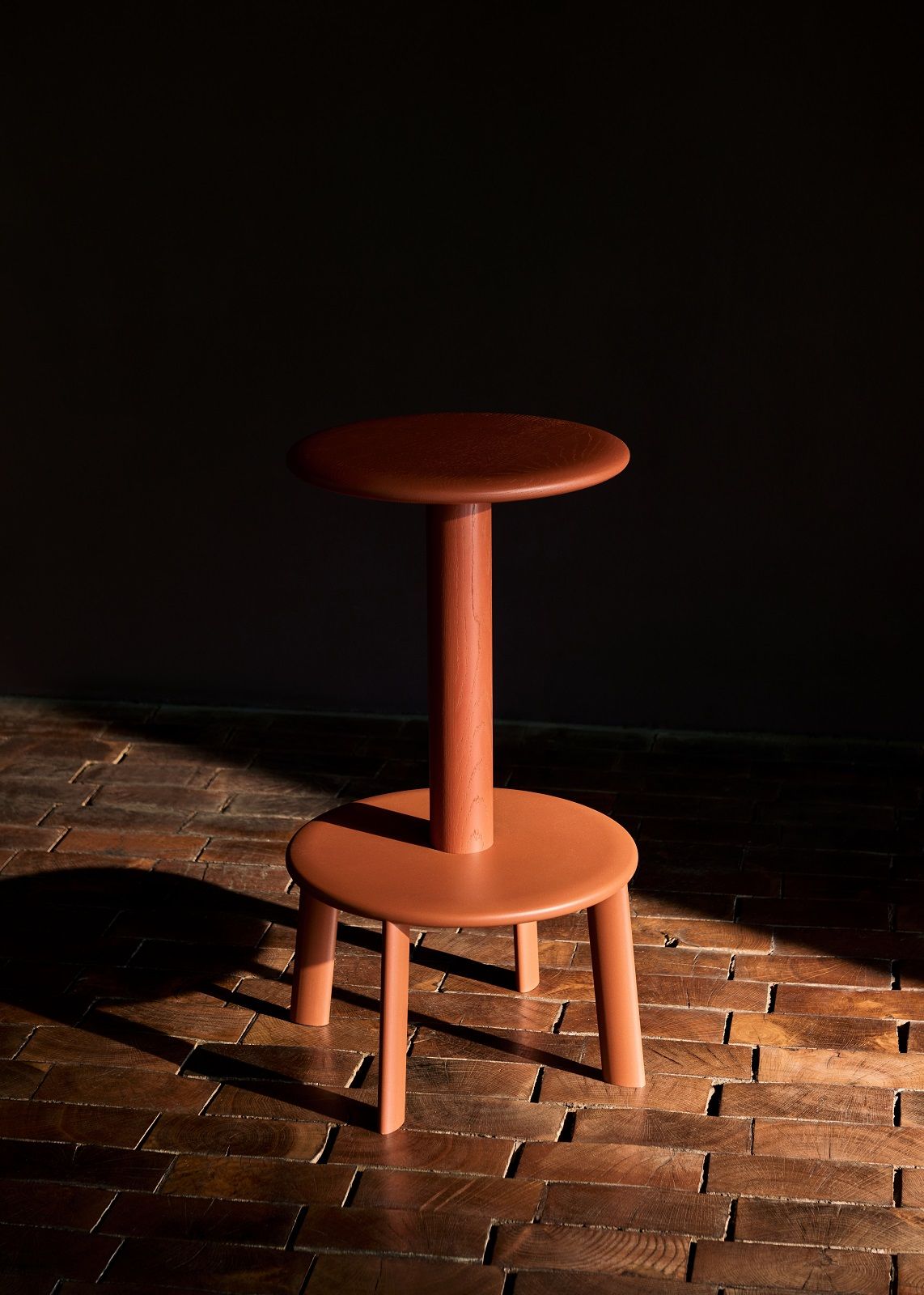 AndTradition Massif AV39 Hocker aus Holz in Terrakotta auf Holzboden, modernes Möbeldesign.