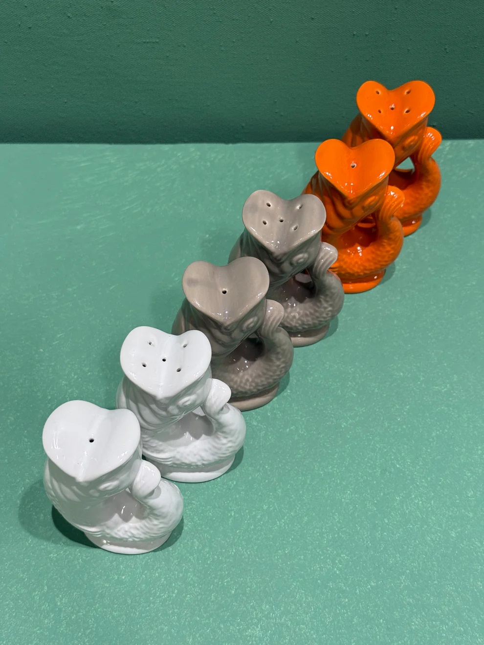 Gluggle Fisch Salz- und Pfefferstreuer Set in Weiß, Grau und Orange auf mintfarbenem Hintergrund.