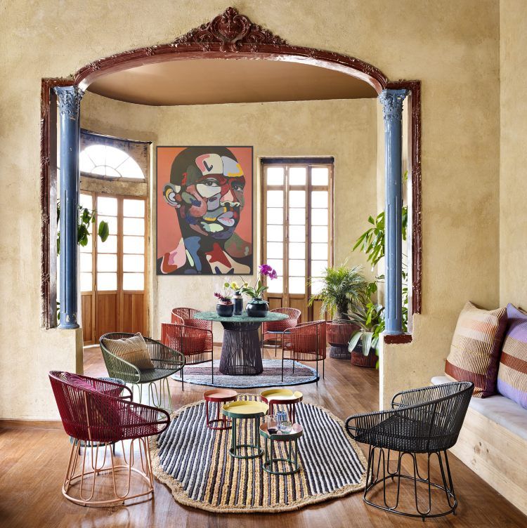 Wohnzimmer mit bunten Rattansesseln, rundem Teppich, Beistelltischen und Kunstwerk. Möbel für stilvolles Wohnen.