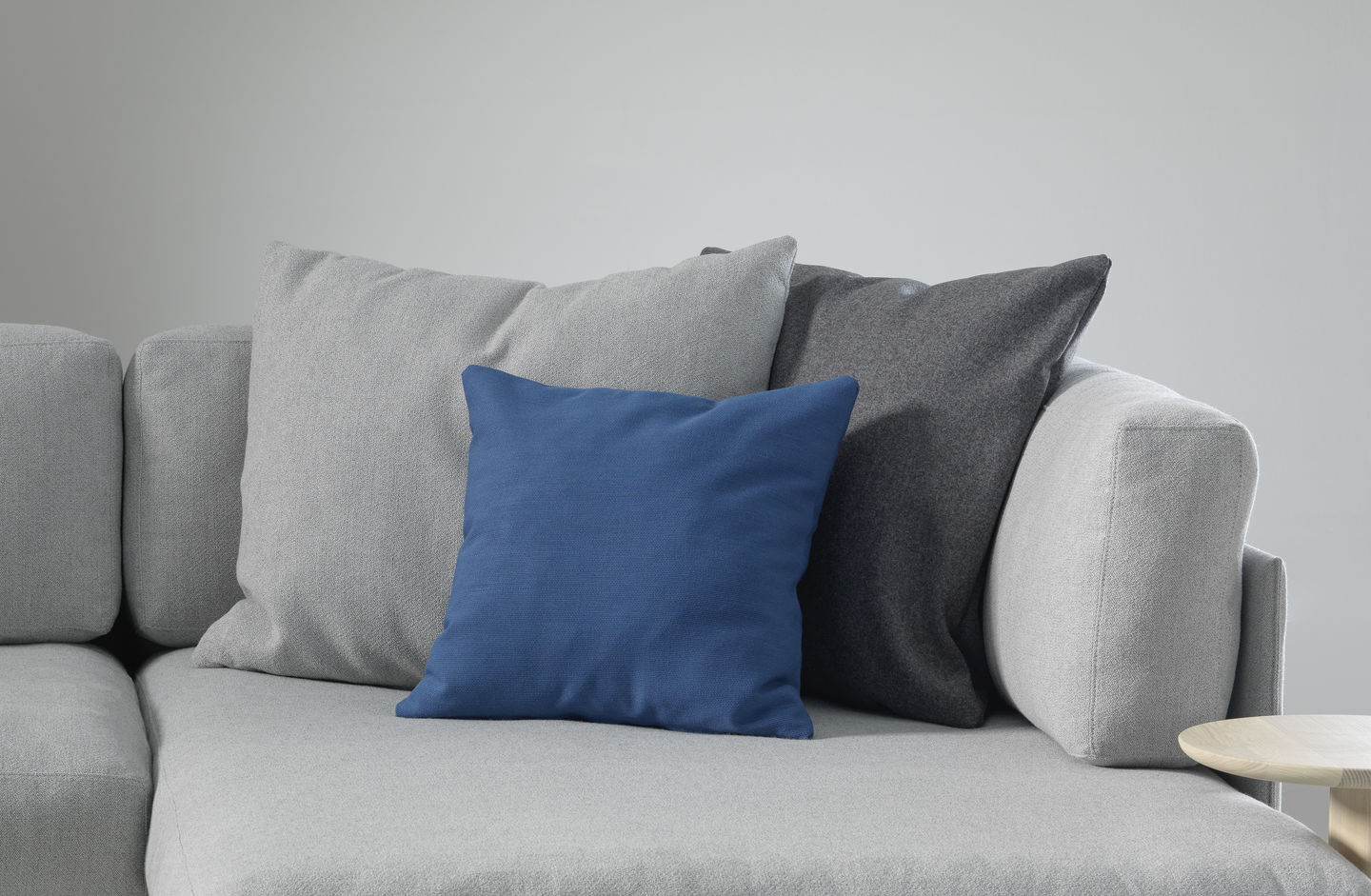 Vitra Kissen: Graues Sofa mit drei dekorativen Sofakissen in Blau, Hellgrau und Dunkelgrau.