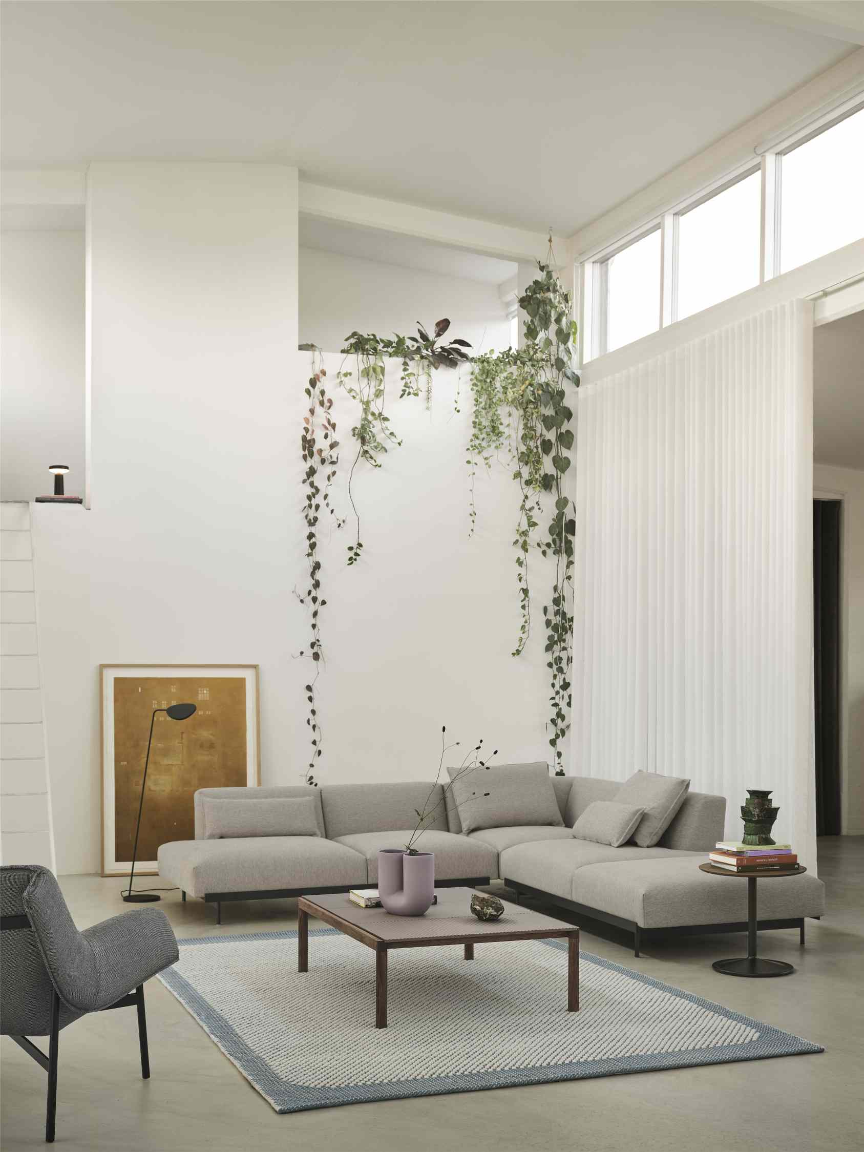 Muuto Couple Couchtisch aus Holz vor grauer Wohnlandschaft mit Dekoration und Teppich.