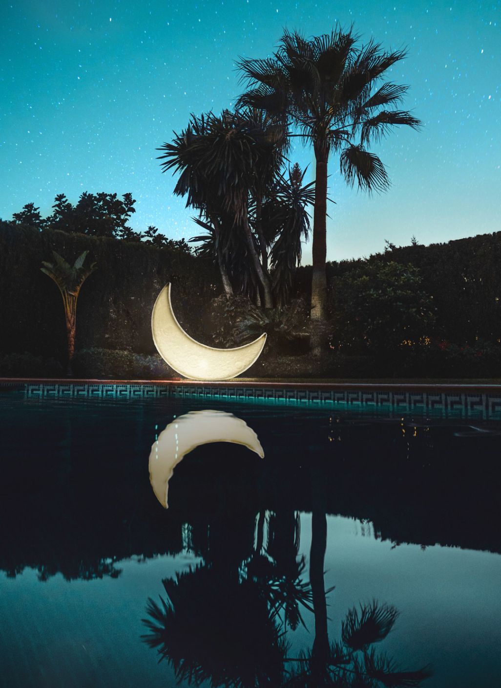 My Moon Lamp von Seletti am Pool mit Spiegelung im Wasser bei Nacht.