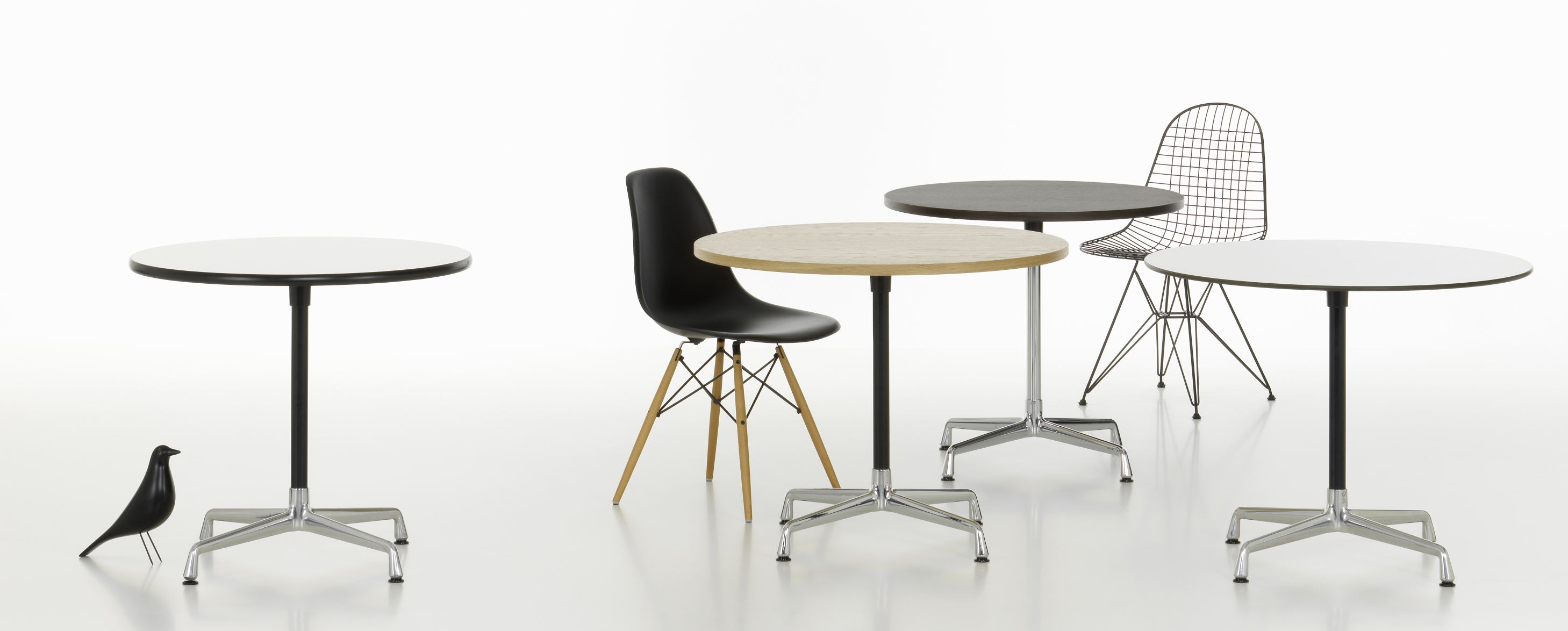 Produktbild: Mehrere runde Eames Contract Table Tische von Vitra mit verschiedenen Tischplatten und Stühlen.