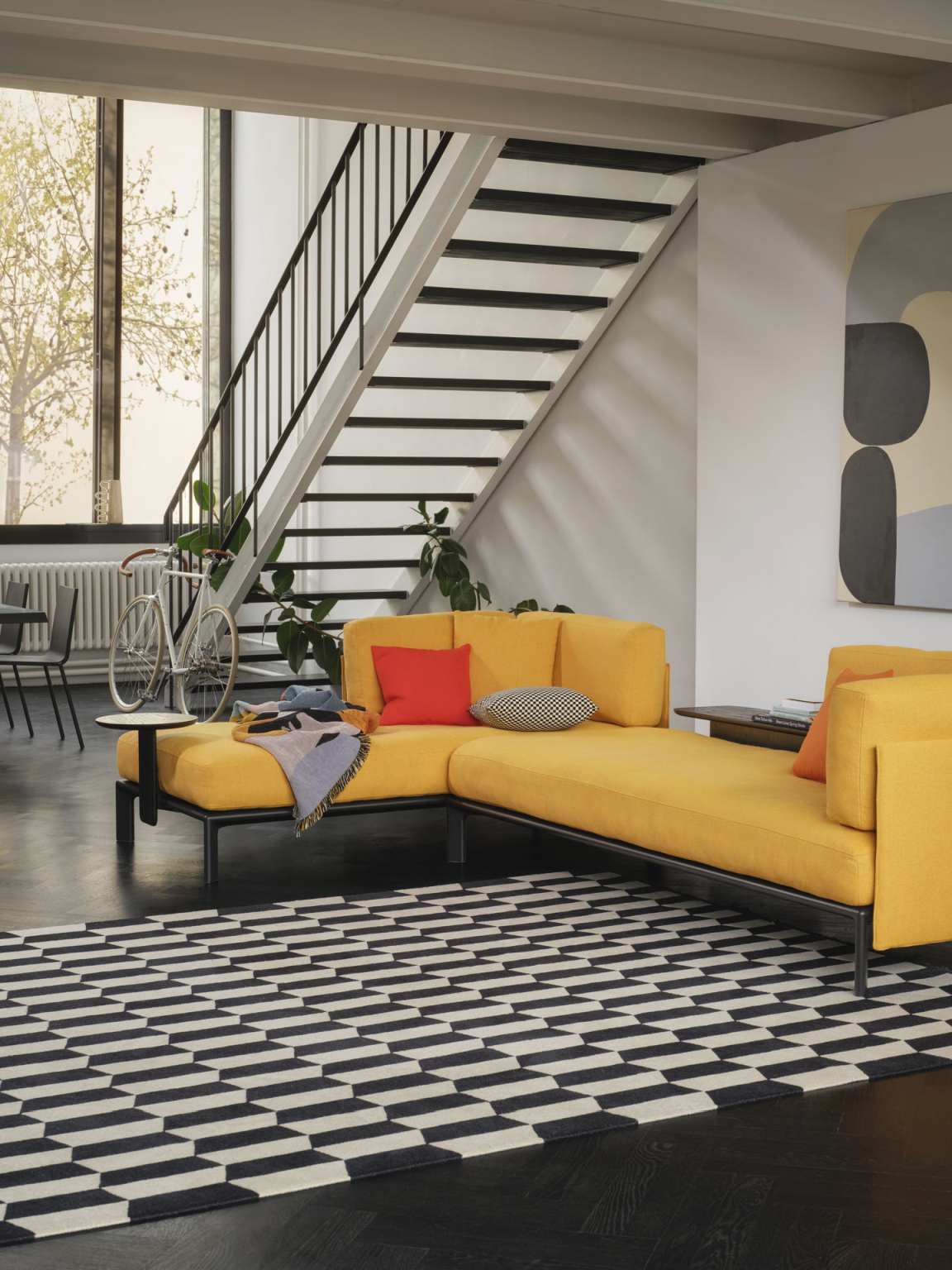 Gelbes modulares Sofa mit schwarzen Metallbeinen, verbunden mit Vitra Anagram Plattformverbinder, in modernem Wohnzimmer.