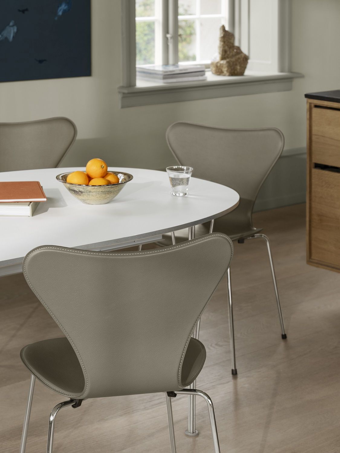 Nahaufnahme eines grauen Siebener Stuhls von Fritz Hansen mit Lederbezug am Esstisch.