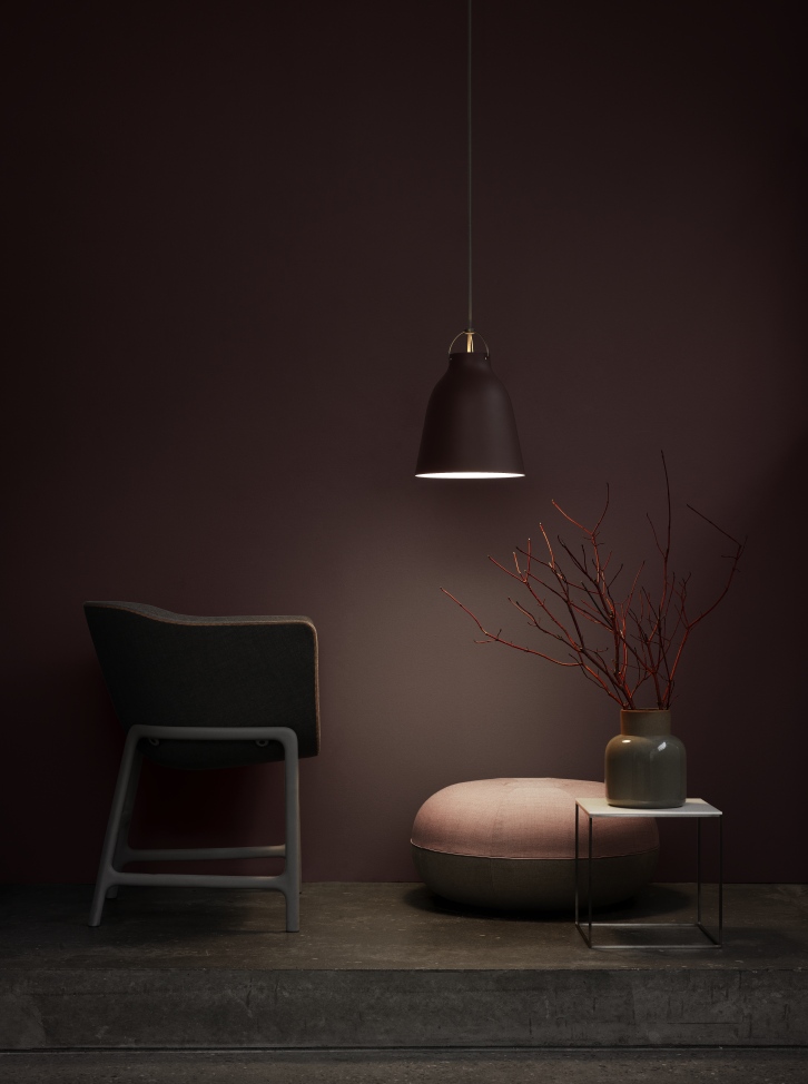Dunkelbraune Caravaggio Pendelleuchte von Fritz Hansen über einem Hocker mit Stuhl und Dekoration.