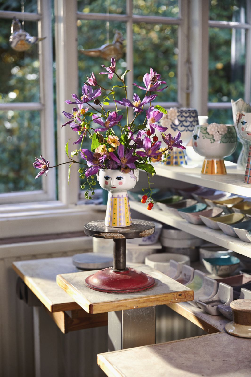 Nahaufnahme der Bjørn Wiinblad Eva Vase H15cm in Lavendel mit Blumen auf einem Werkstatttisch.