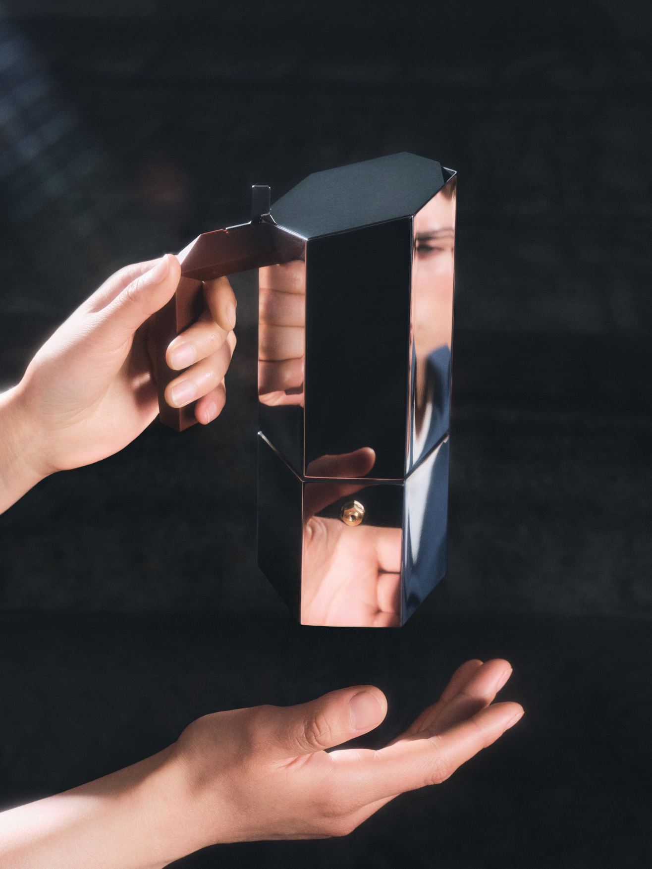 Hände halten und präsentieren den Menhir Espressokocher von Alessi für sechs Tassen, modernes Design.