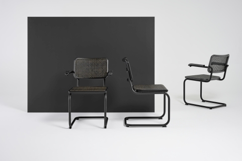 Drei schwarze S 64 V Stahlrohr Freischwinger Stühle von Thonet mit Wiener Geflecht vor schwarzem Hintergrund.