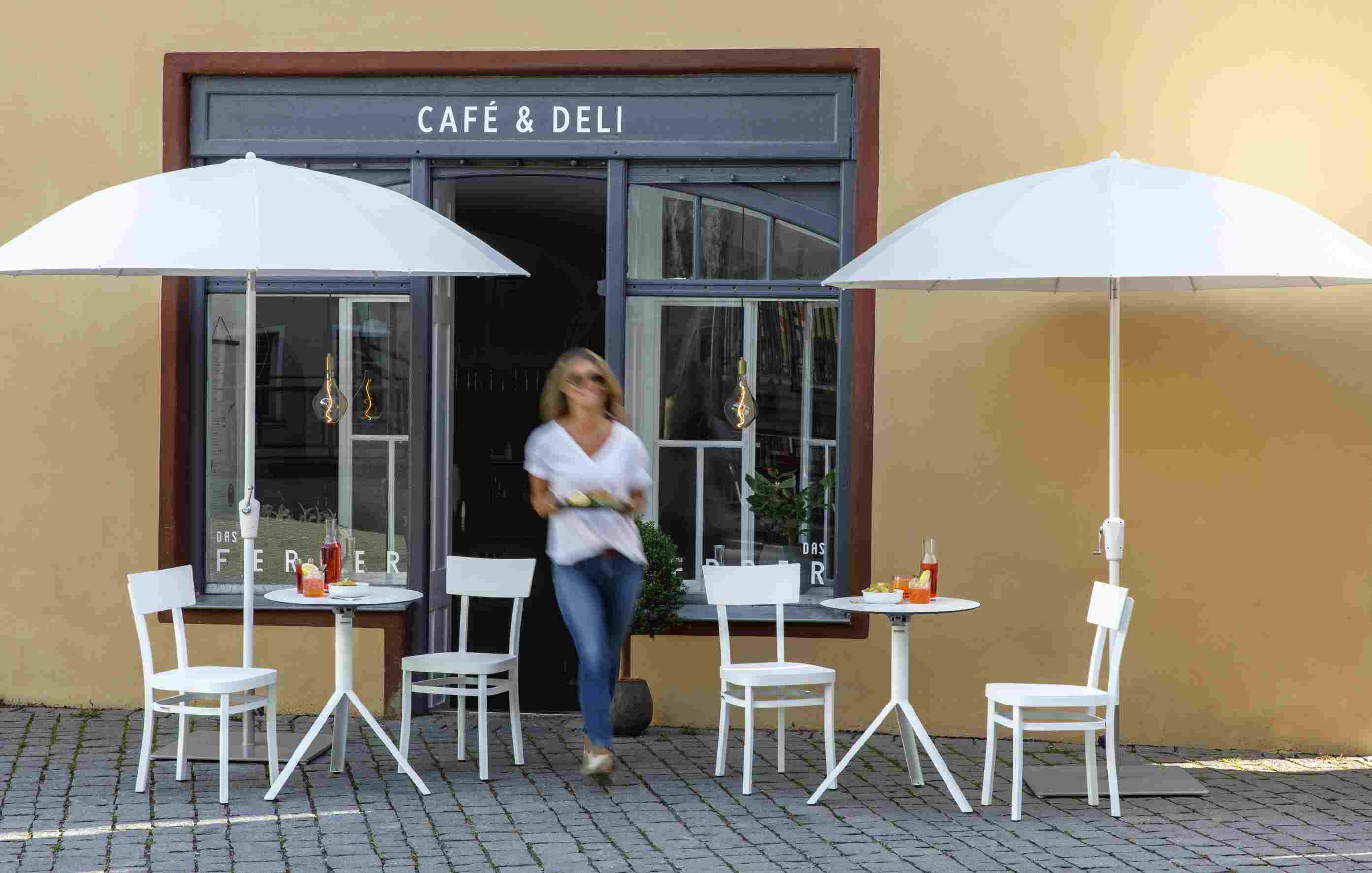 Weishäupl Sonnenschirm, Pagodenschirm in Weiß vor Café mit Tischen und Stühlen.