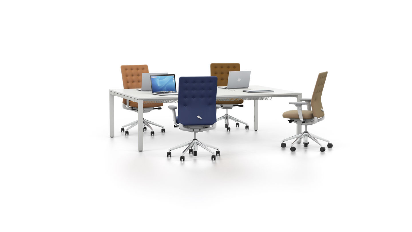ID Trim Bürodrehstuhl von Vitra in verschiedenen Farben um einen weißen Konferenztisch mit Laptops.