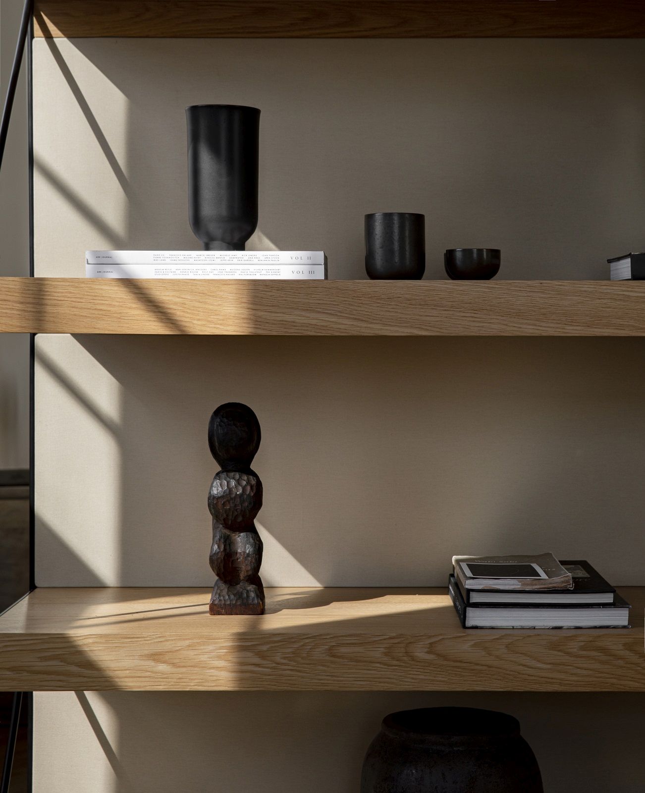 Detailaufnahme des Audo Copenhagen Zet Storage System Regals mit Deko-Objekten und Büchern auf hellen Holzregalböden.