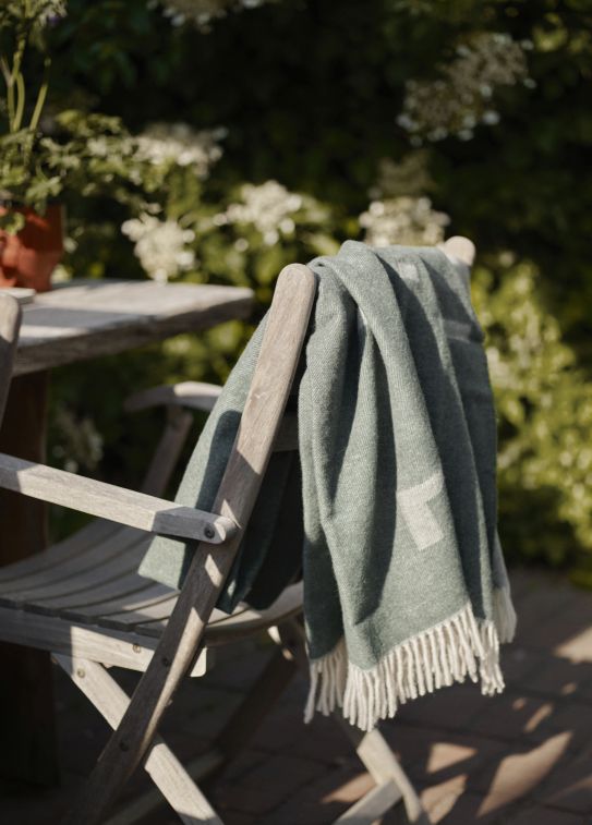 Selandia Armchair Sessel von Skagerak by Fritz Hansen mit grüner Decke im Garten.