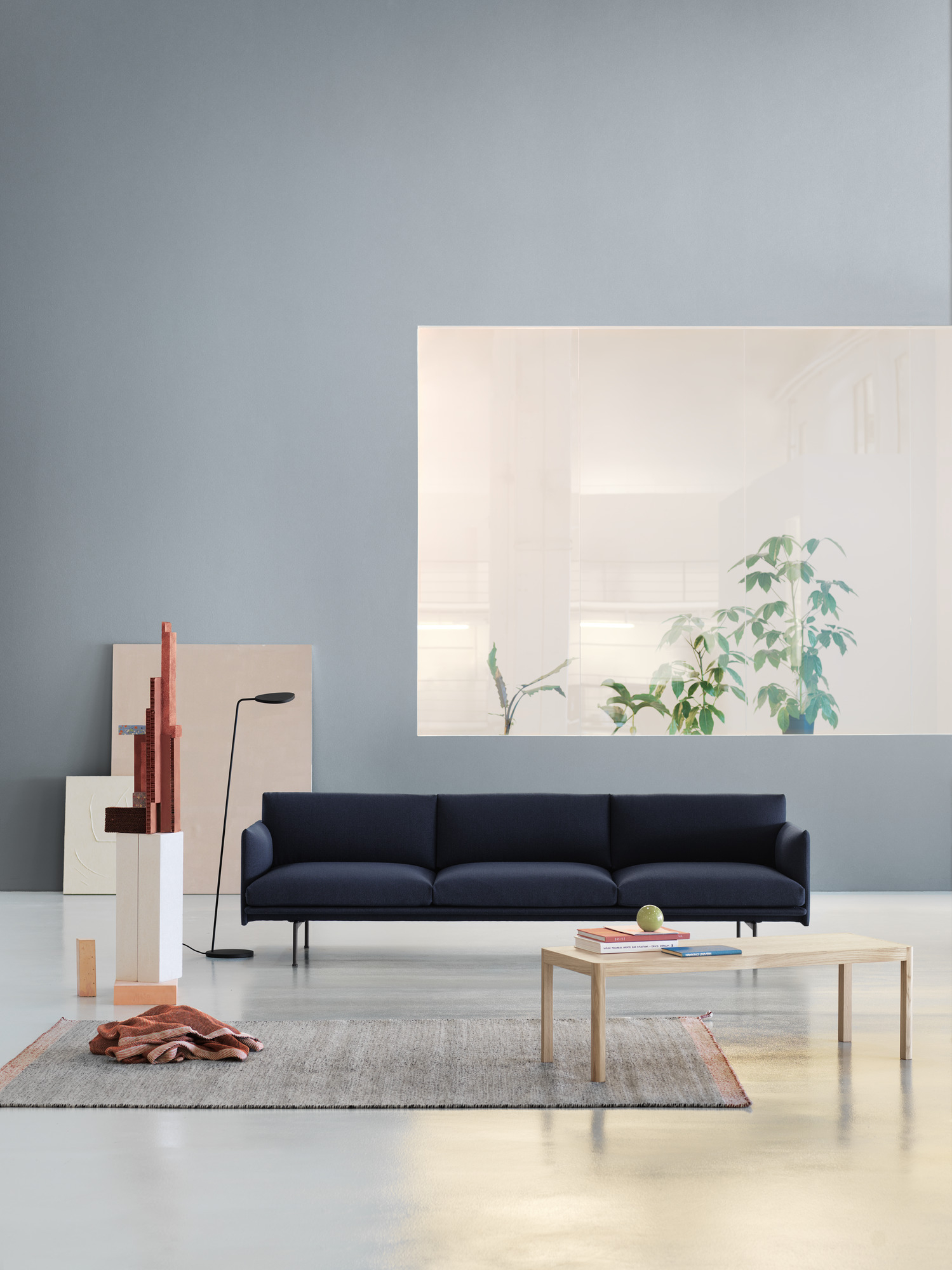 Muuto Workshop Couchtisch aus Eiche vor blauem Sofa und grauem Teppich im modernen Wohnzimmer.