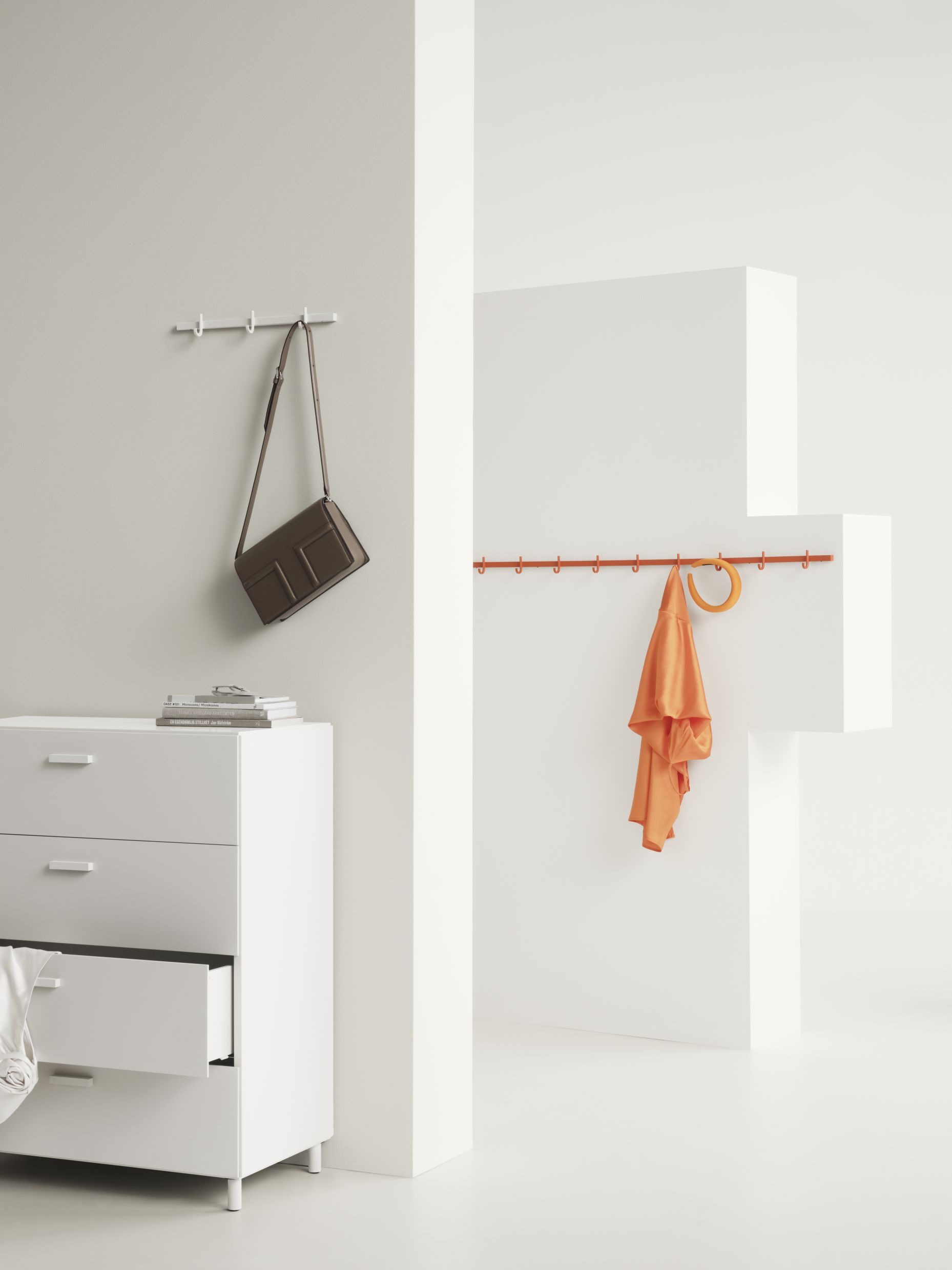 Weiße Relief Hakenleiste von String Furniture, 123cm breit, mit Tasche und Kleidung an der Wand.
