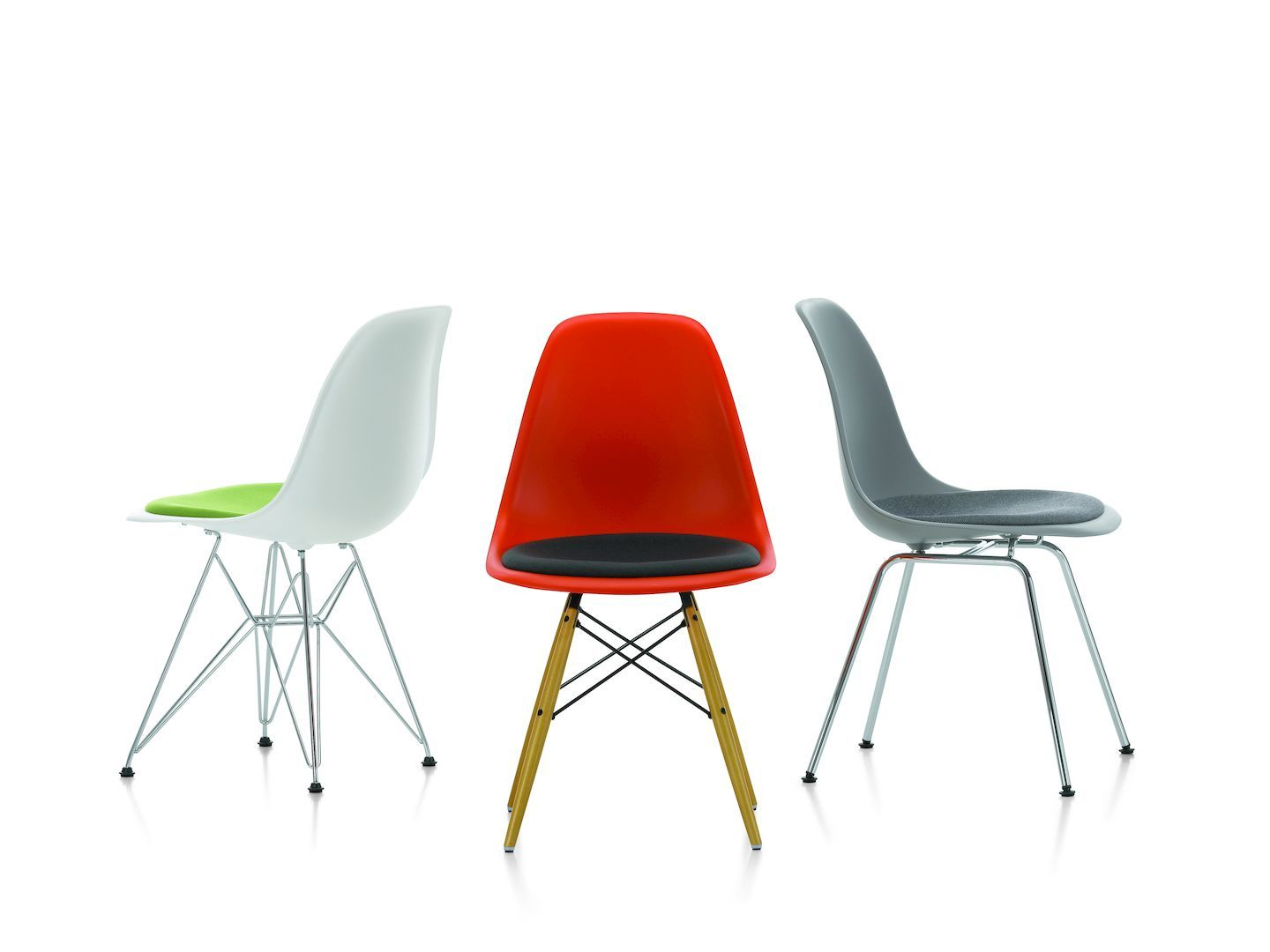 Drei Eames Plastic Side Chairs DSR von Vitra in Weiß, Rot und Grau mit Sitzpolster.