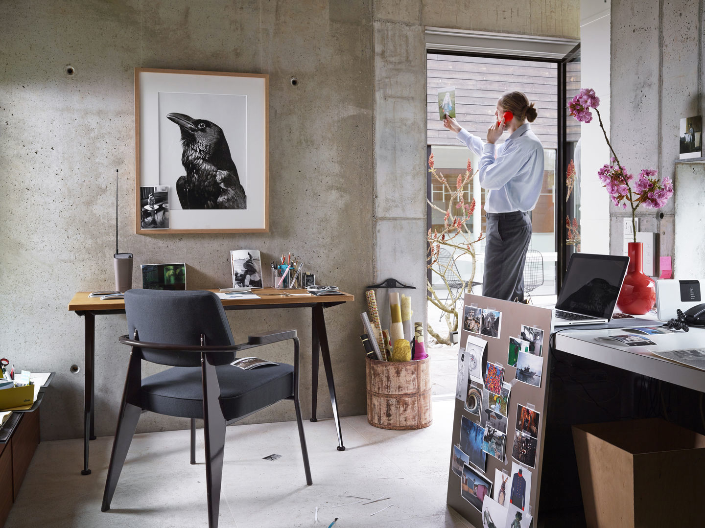 Vitra Fauteuil Direction Sessel in grau vor Schreibtisch in modernem Büro mit Betonwand.