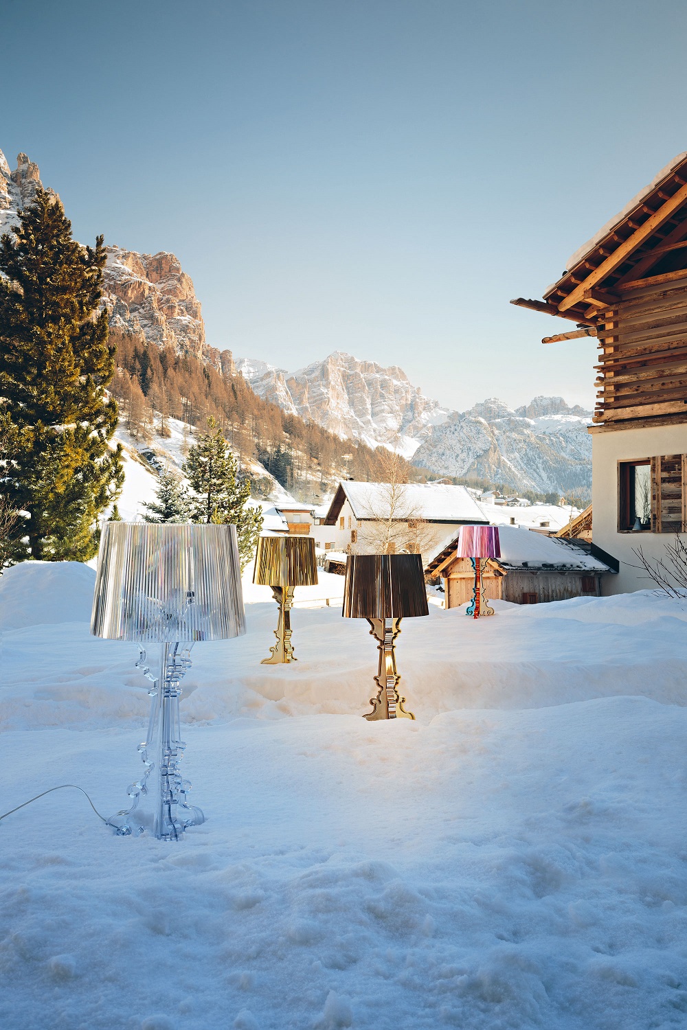Kartell Bourgie Tischleuchten in verschiedenen Farben im Schnee vor verschneiter Bergkulisse.