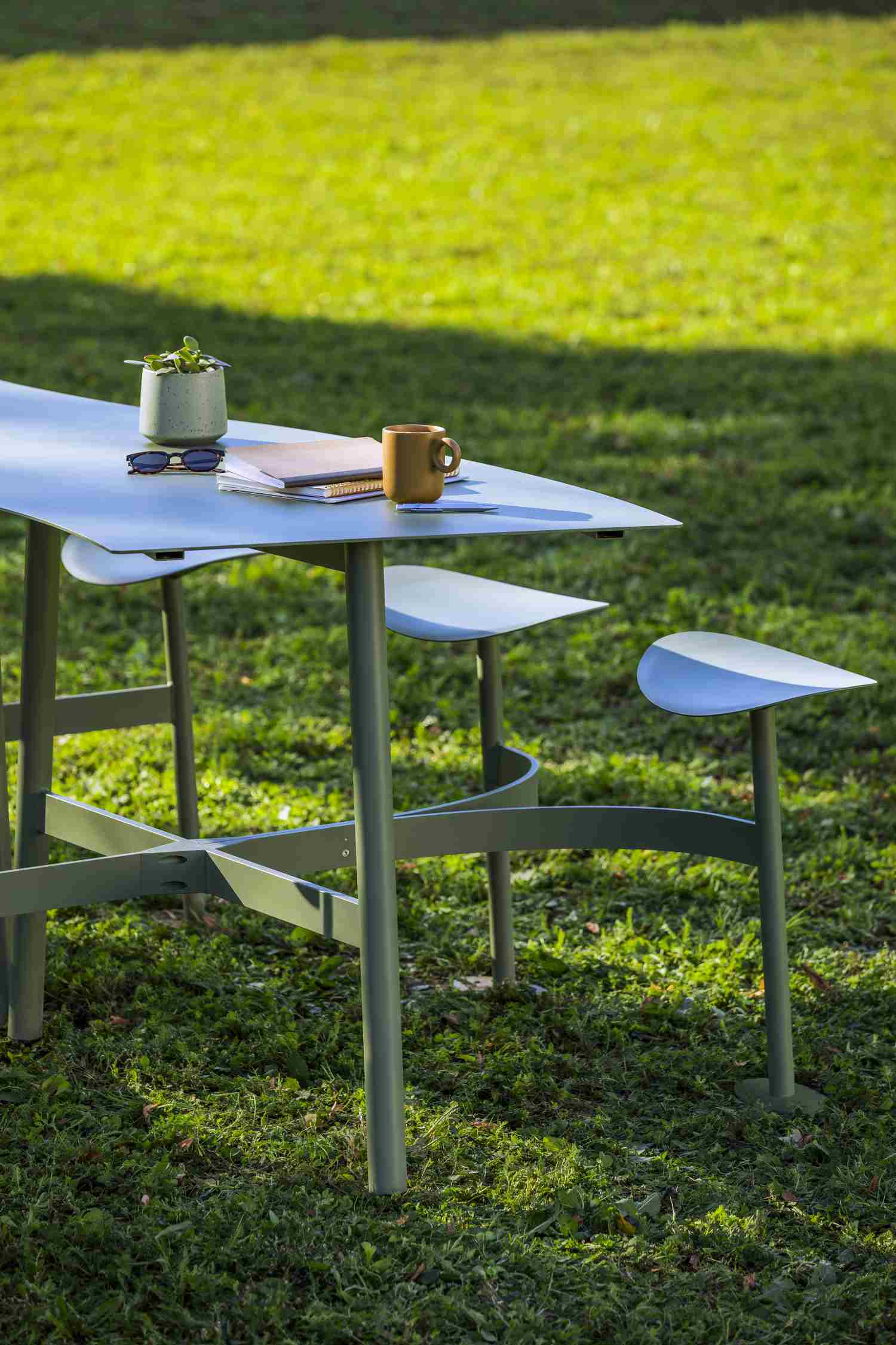 Fermob Bolder Theke Outdoor auf Rasen mit Kaffeetasse, Notizbuch und Sonnenbrille für entspanntes Arbeiten im Freien.