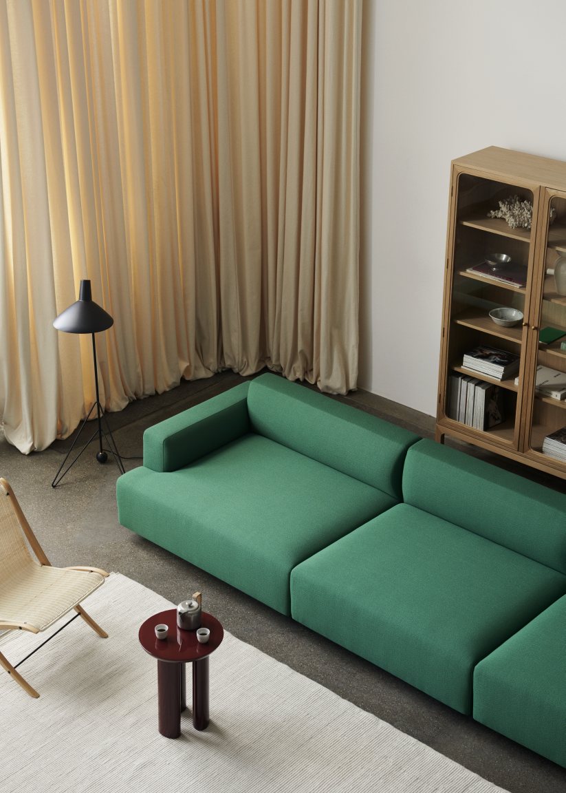 AndTradition Collect Rug SC84, ein weißer Wollteppich unter einem grünen Sofa in einem modernen Wohnzimmer.