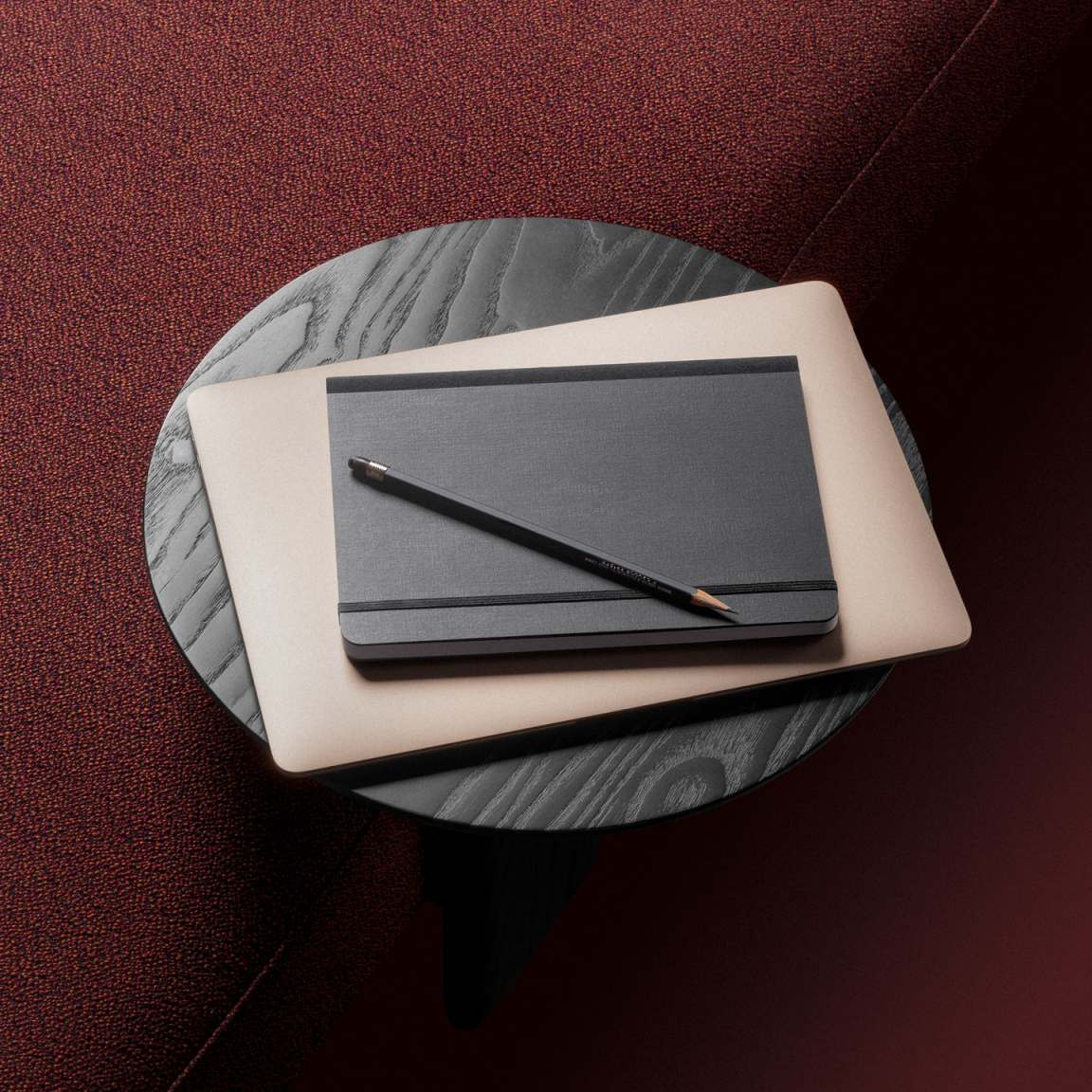 Anagram Anstecktisch von Vitra, runde Tischplatte in Schwarz mit Laptop, Notizbuch und Bleistift.