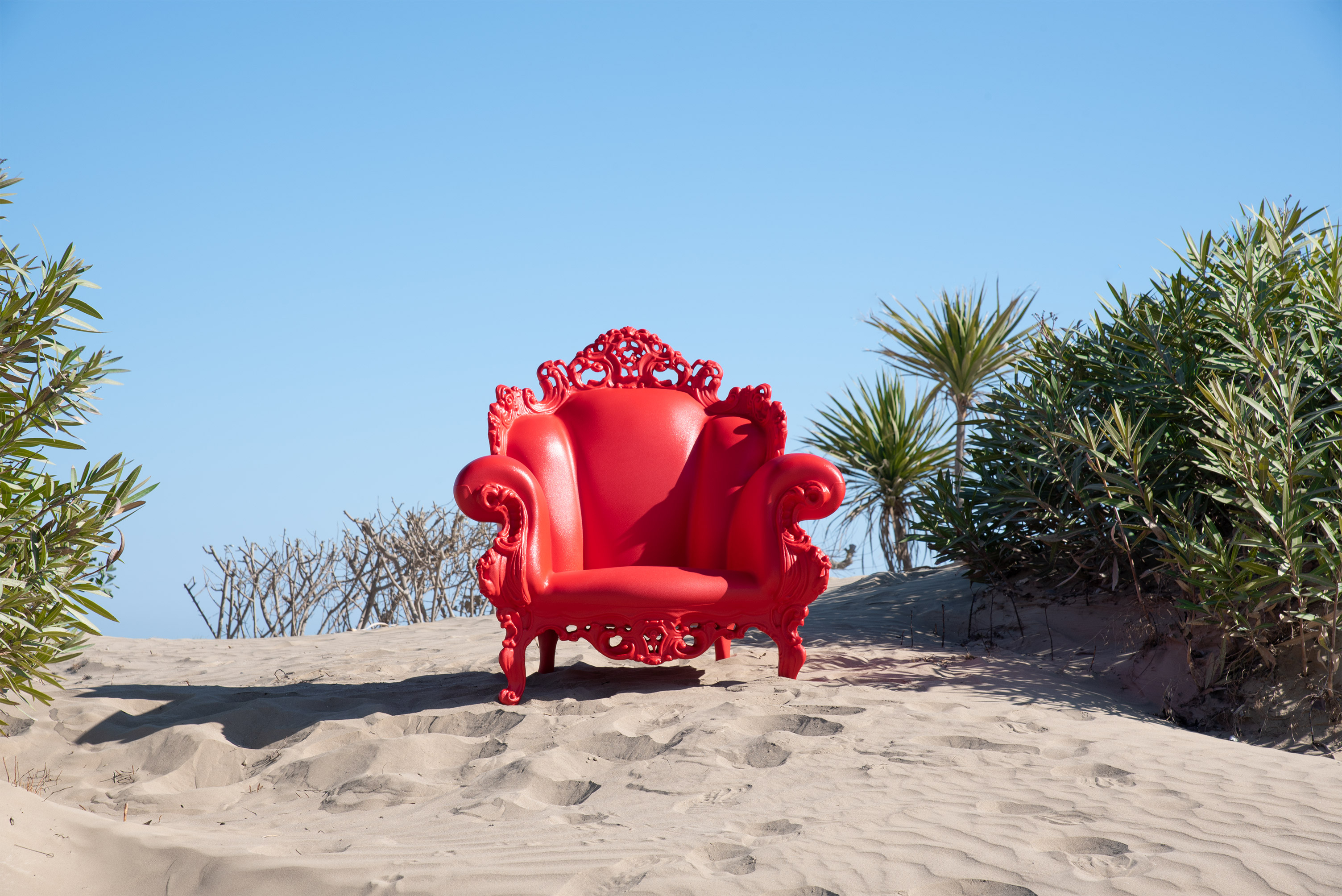 Roter Proust Sessel Outdoor von Magis auf Sanddüne vor blauem Himmel. Design Gartenmöbel.