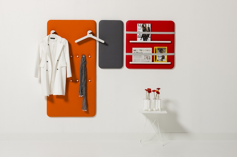 Cascando Pillow Wall Paneele: Orangefarbene Garderobe, graue Pinnwand und rotes Magazinboard an weißer Wand.