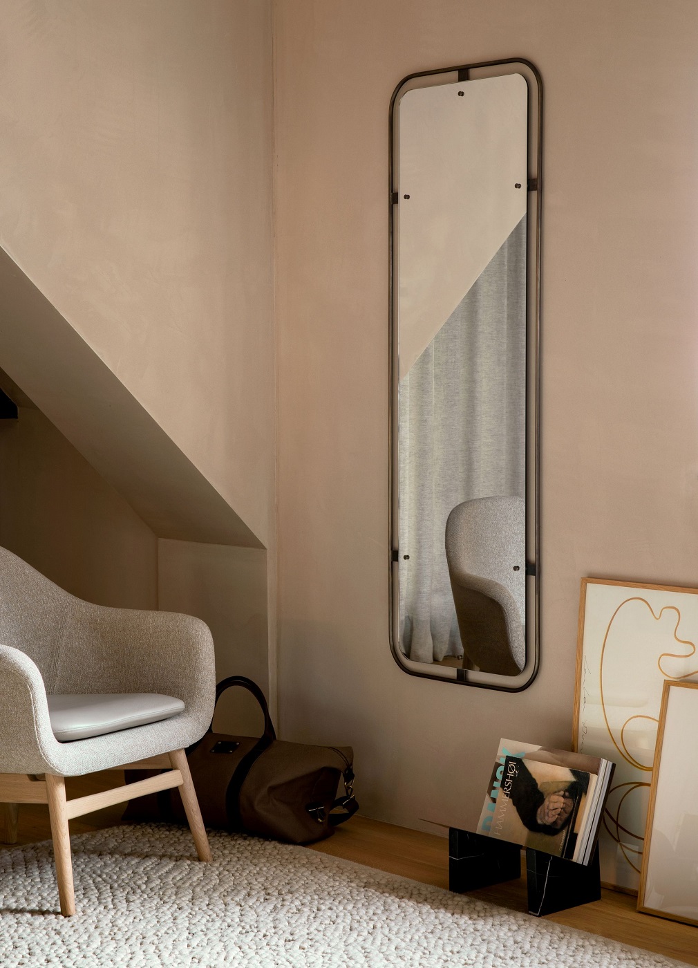 Audo Copenhagen Gravel Rug Teppich in hellem Wohnraum mit Sessel und Spiegel.