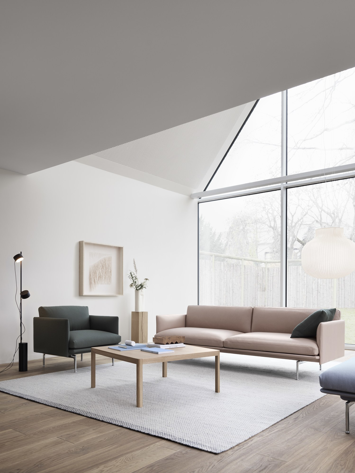 Helle Wohnzimmer-Szene mit Muuto Post Floor Lamp Stehleuchte, Sofa, Sessel und Teppich.