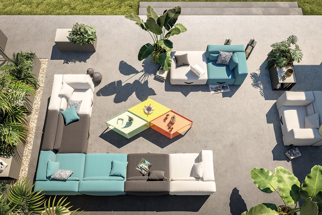 Luftaufnahme: Modulares Conmoto Outdoor Sofa mit anthrazitfarbenen Wurfkissen und bunten Tischen auf einer Terrasse.