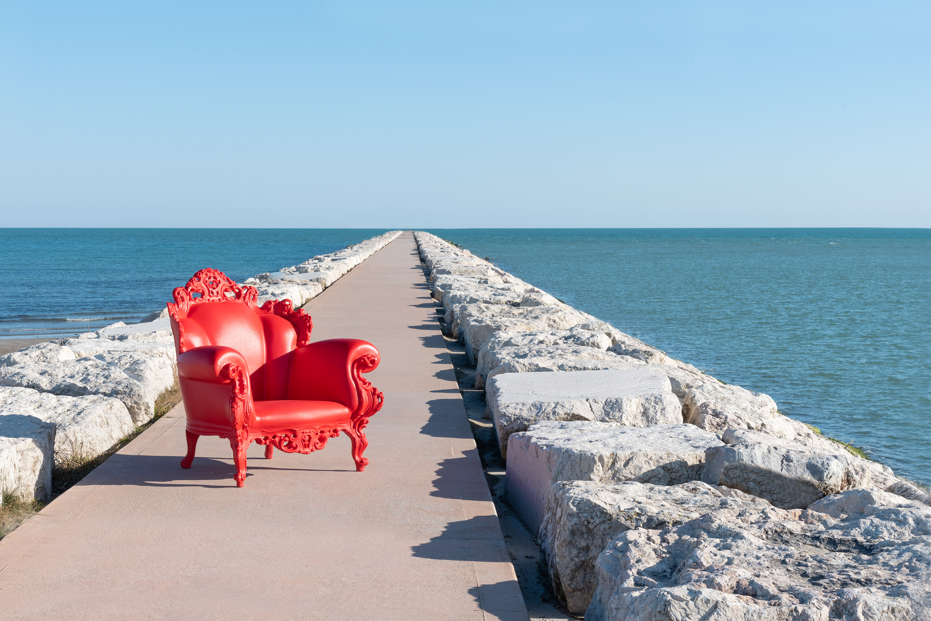 Roter Proust Sessel Outdoor von Magis auf einem Steg mit Meer im Hintergrund.
