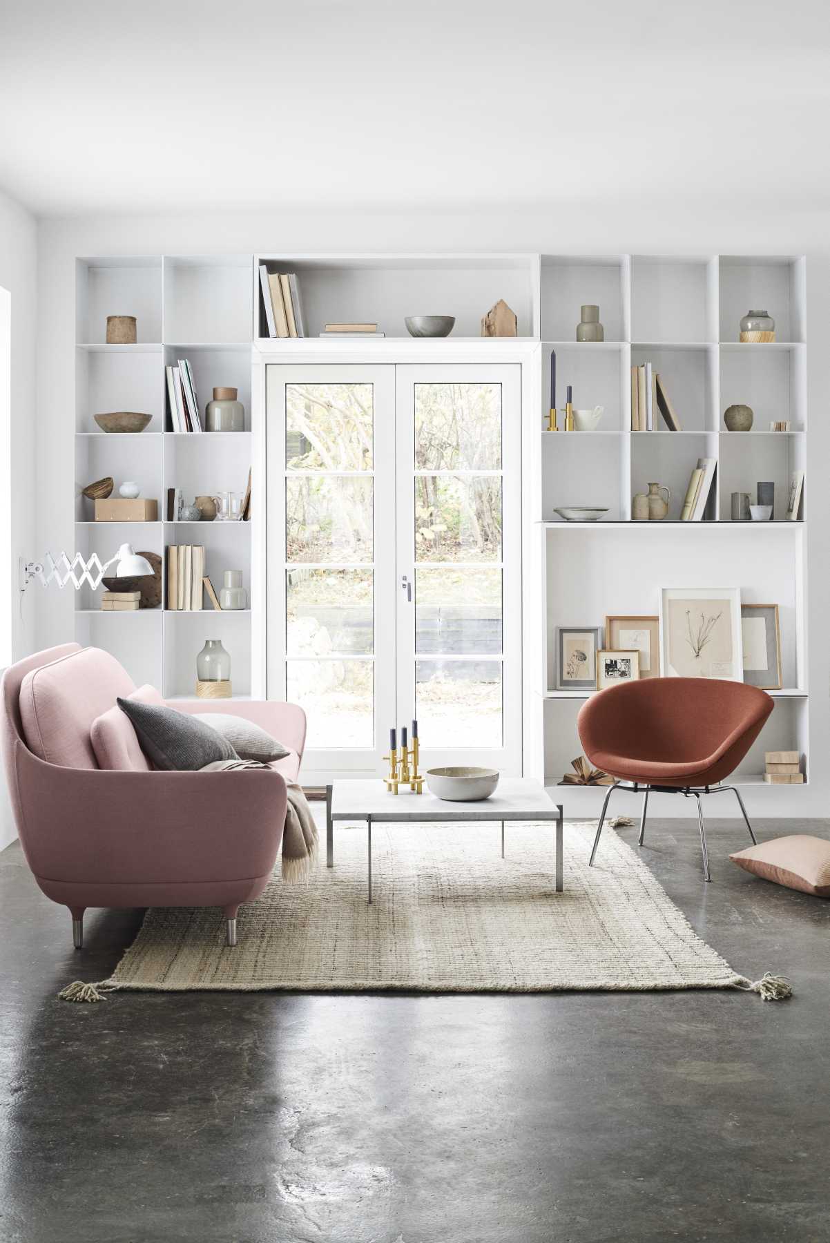 Rosa Fritz Hansen Pot Sessel und brauner Sessel in modernem Wohnzimmer mit Bücherregal und Teppich.