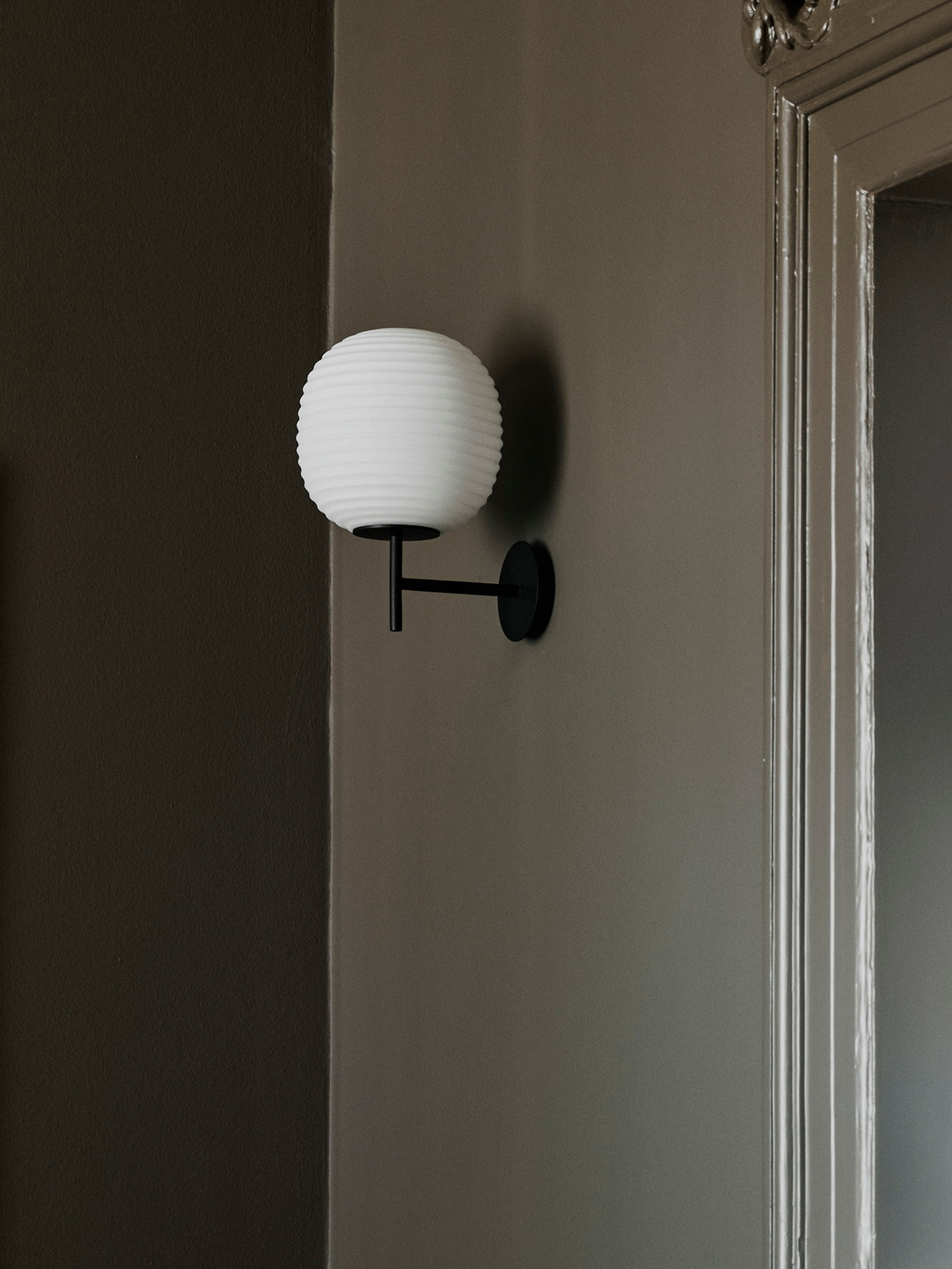 Nahaufnahme der New Works Lantern Wandleuchte small mit weißem Schirm und schwarzer Halterung.