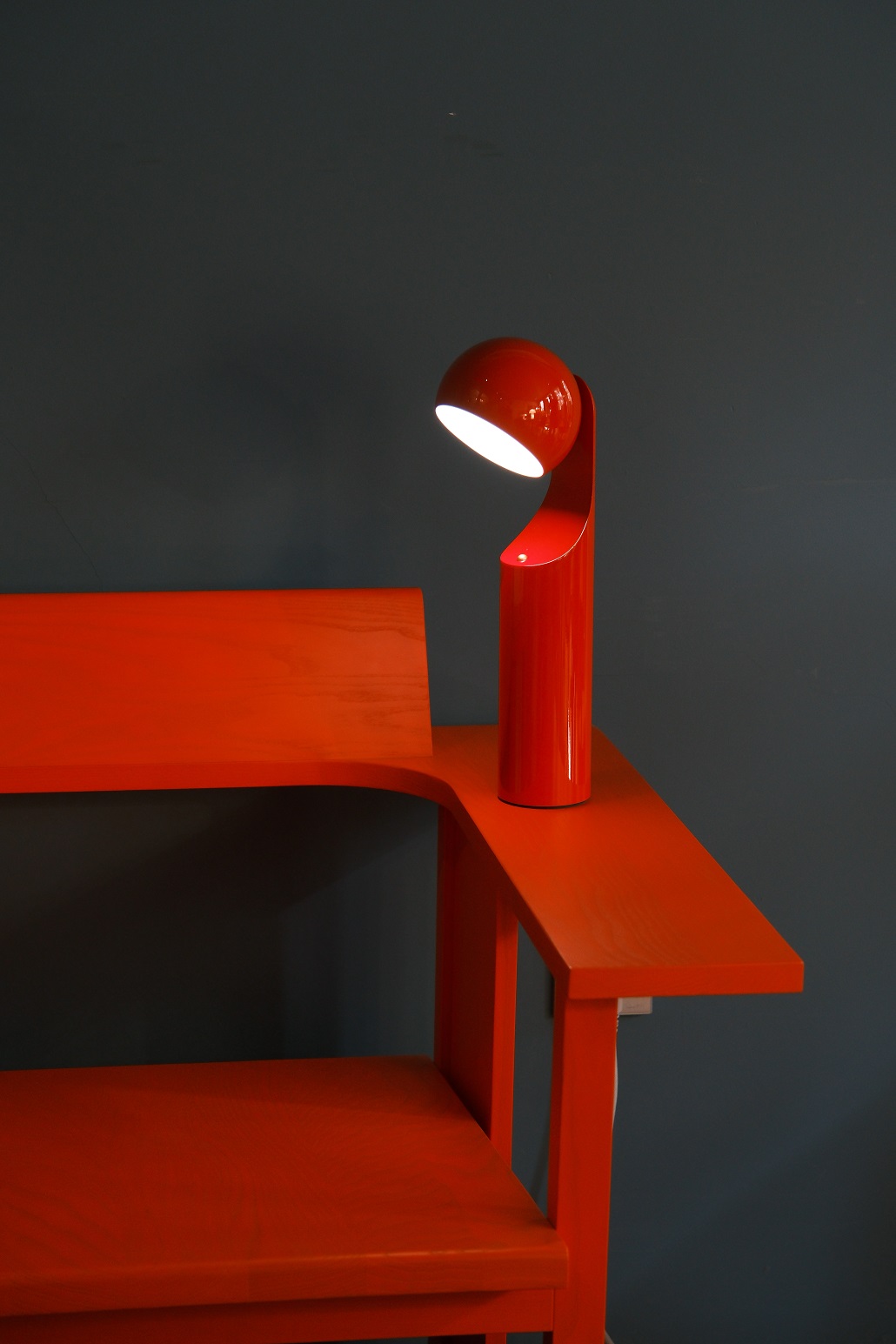 Rote Mono Portable Akkuleuchte von house of home als Tischleuchte auf einem roten Tisch.