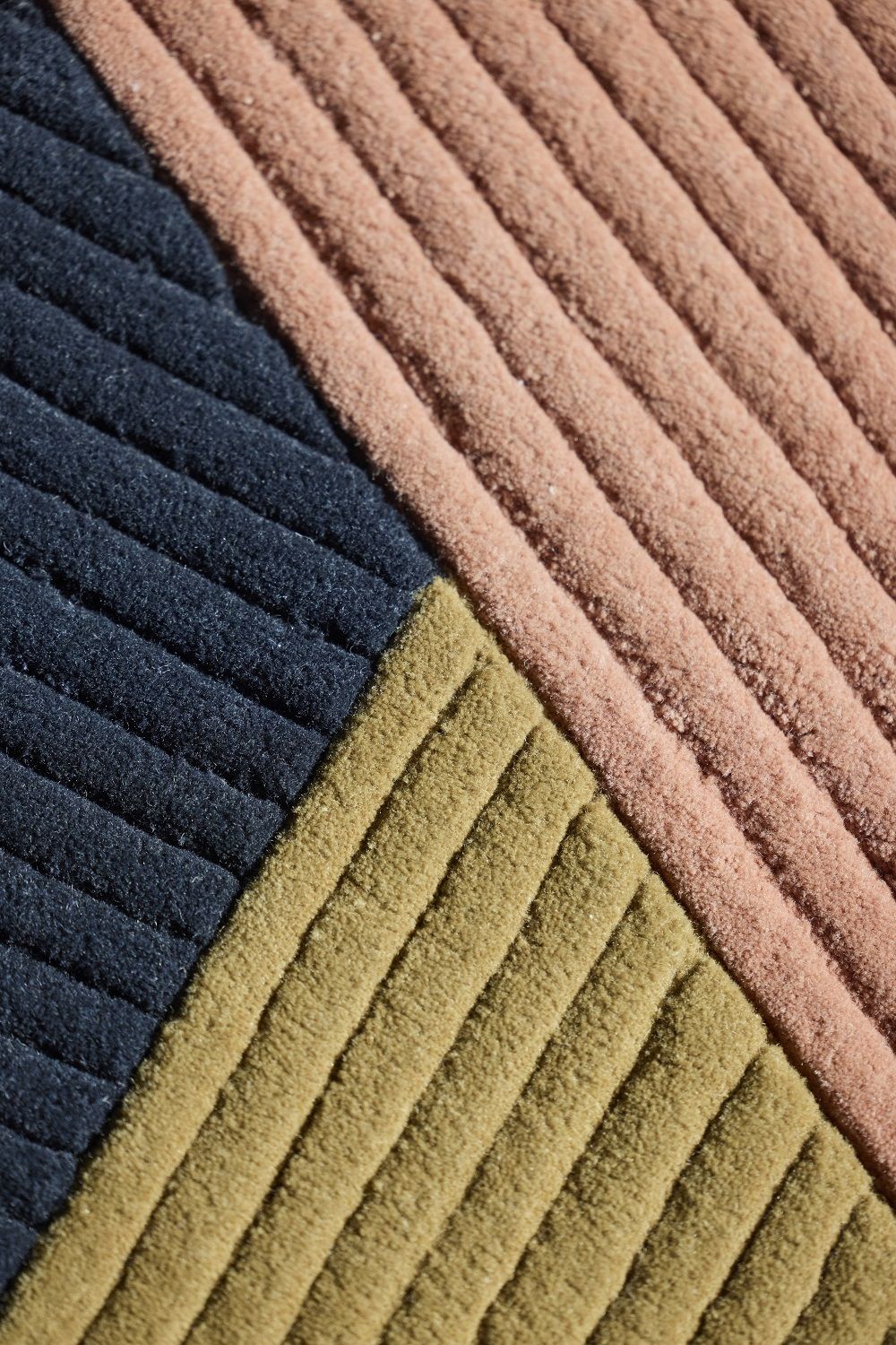 Detailaufnahme des Row Rug Circular Teppichs Northern in Blau, Olivgrün und Rosa mit gerippter Textur.