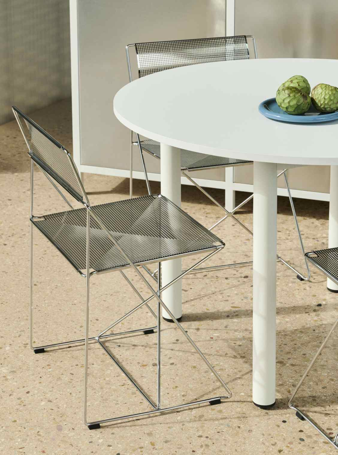 Heller Annex Table Esstisch von Hay mit Stühlen und tropischen Früchten auf blauem Teller.