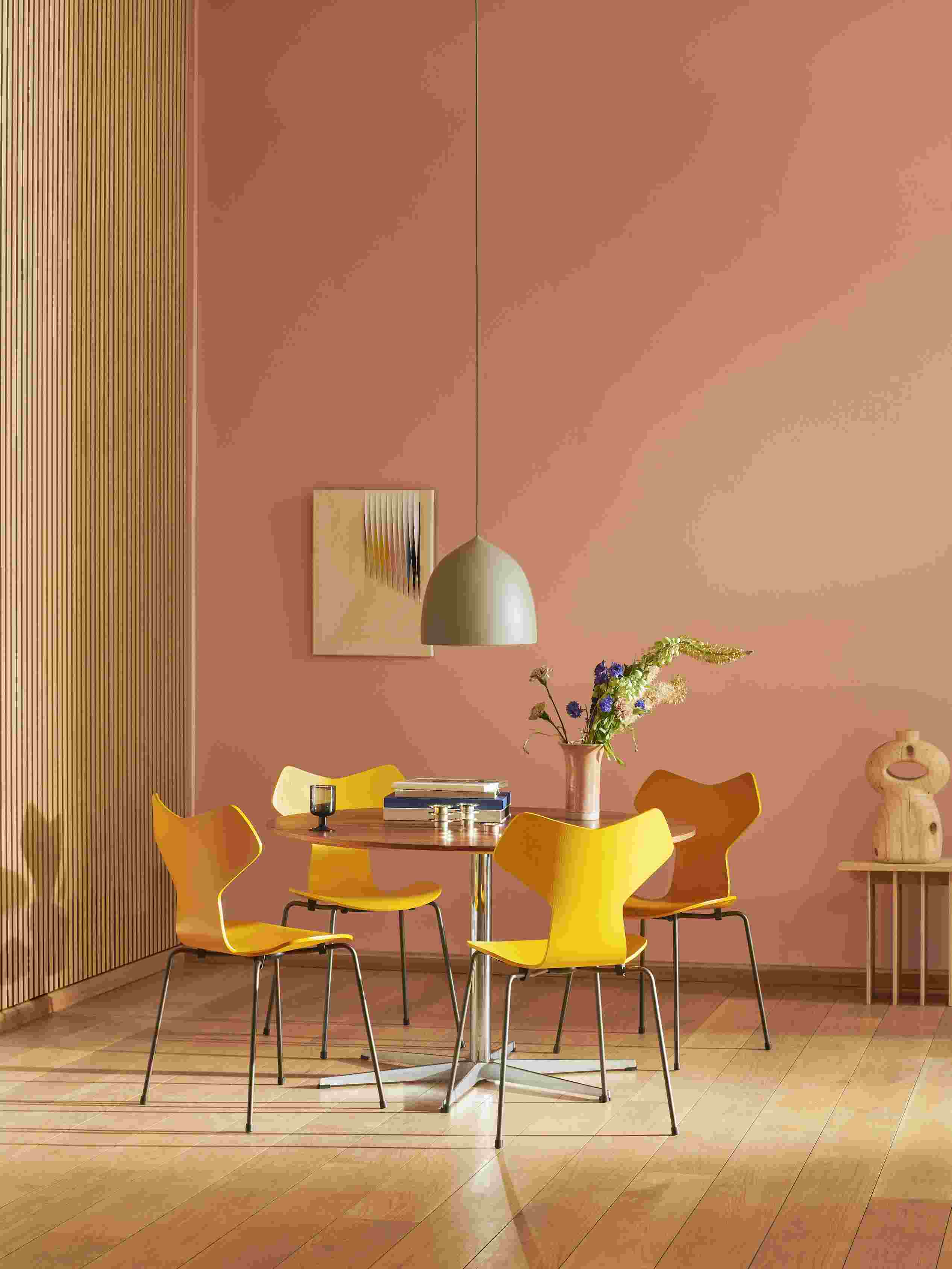 Gelbe Fritz Hansen Grand Prix Stühle um einen runden Esstisch in einem modern eingerichteten Esszimmer.