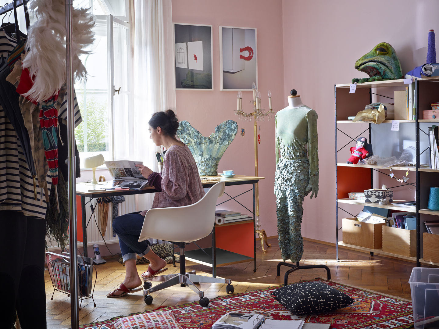 Frau sitzt an Schreibtisch auf einem weißen Eames Plastic Arm Chair von Vitra.