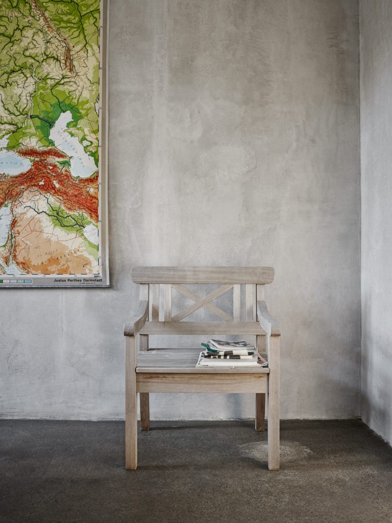 Drachmann Stuhl von Skagerak by Fritz Hansen, grauer Holzstuhl mit Zeitschriften vor grauer Wand.