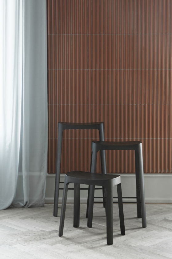 Zwei graue Crofton Barhocker von Please wait to be seated vor einer strukturierten Wand.