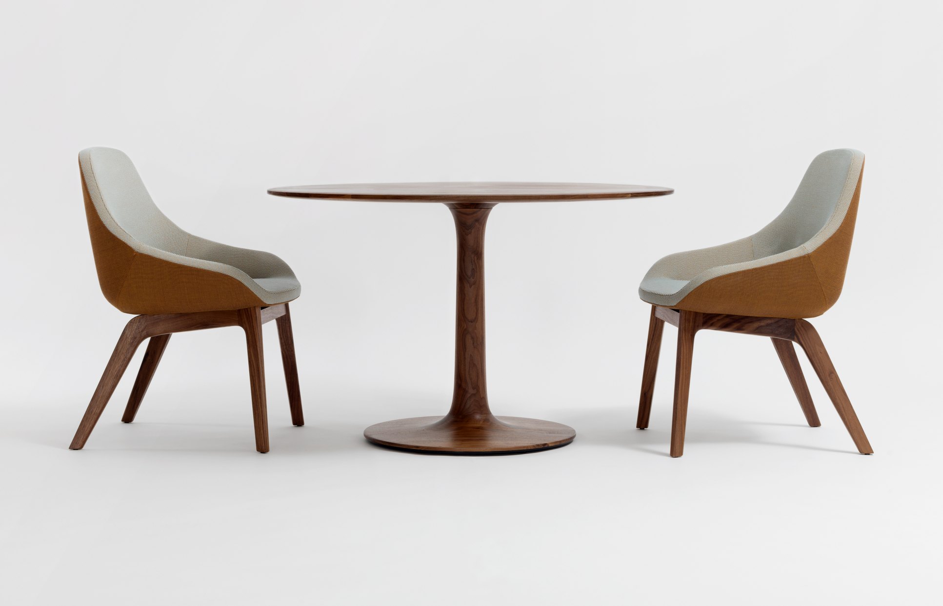 Morph Dining Chair Stuhl von Zeitraum mit braunem Holzrahmen und hellgrauem Stoffbezug an rundem Esstisch.