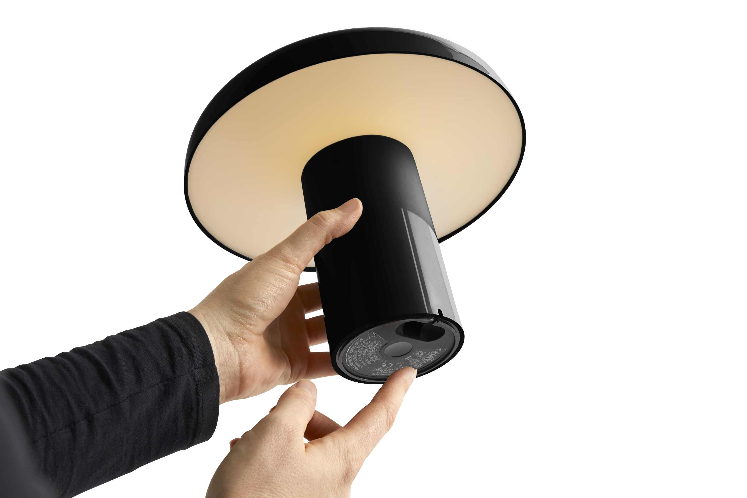 Nahaufnahme der schwarzen Hay Pao Portable Lamp Akkuleuchte, die von einer Hand bedient wird.