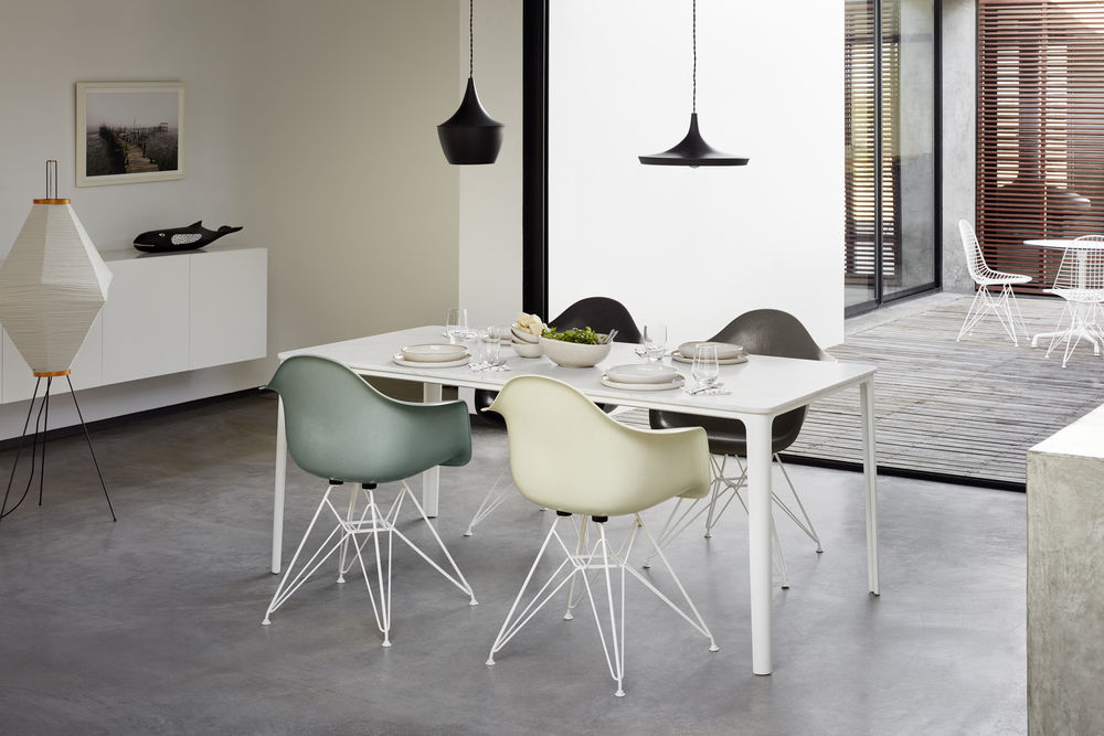 Esszimmer mit weißem Tisch, Eames Stühlen in verschiedenen Farben und moderner Beleuchtung.
