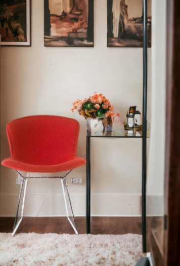Roter Bertoia Stuhl mit Vollpolsterung von Knoll International neben einem Beistelltisch mit Blumen.