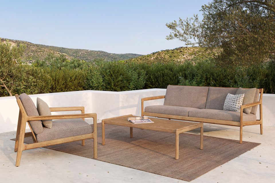 Ethnicraft Jack Couchtisch aus Teakholz mit Sofa und Sessel im Outdoor-Bereich.