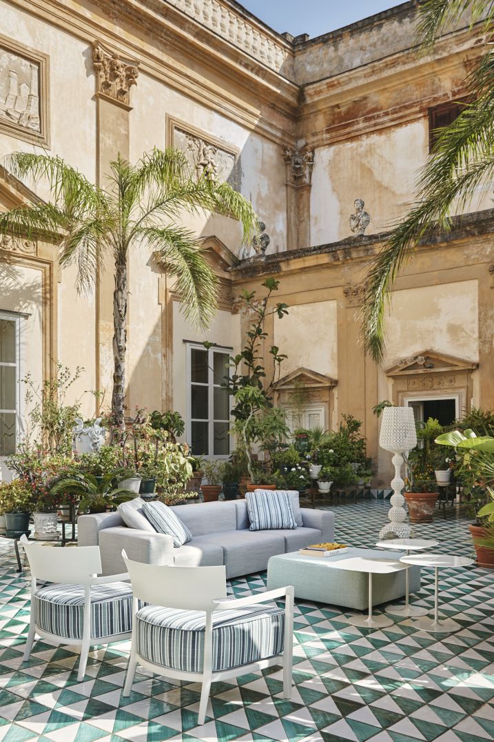 Cara Mat Outdoor Sessel von Kartell auf einer Terrasse mit Pflanzen und mediterraner Architektur.