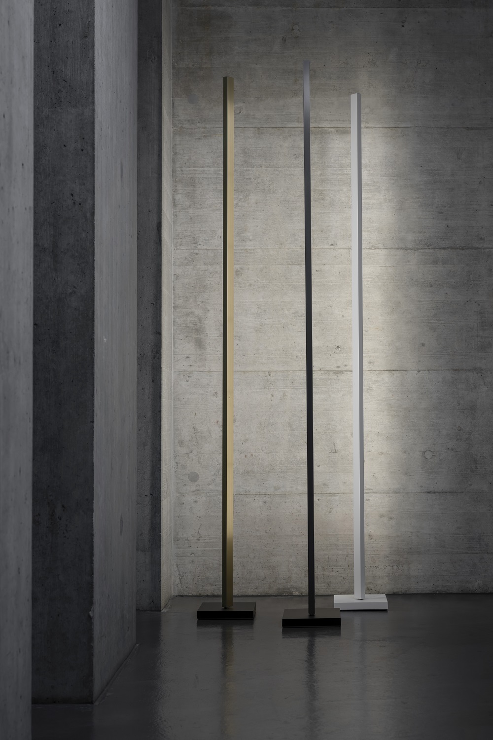 Zen Floor Lamp Stehleuchte in Gold, Schwarz und Weiß vor einer Betonwand.