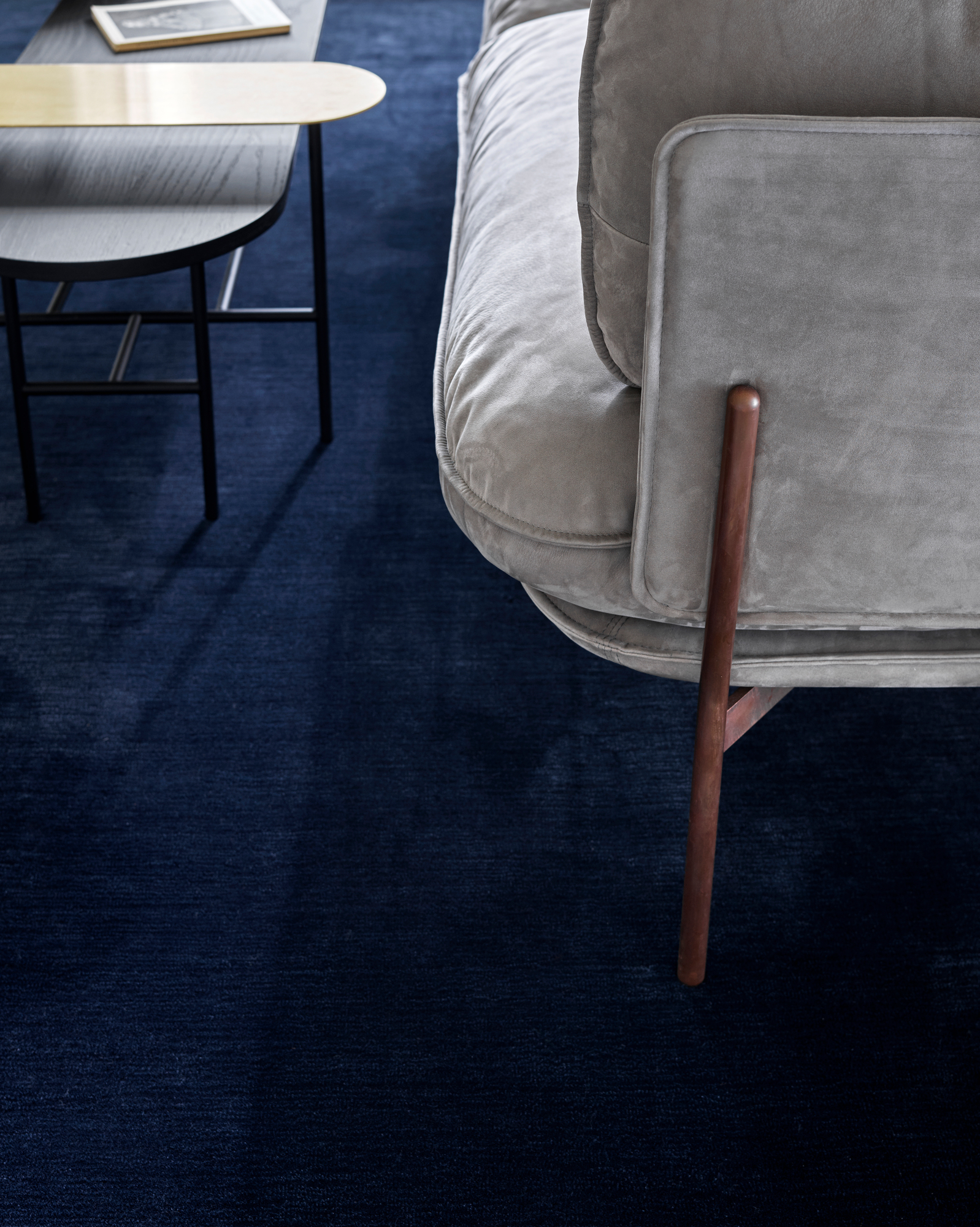 Detailaufnahme des Cloud Sofas von AndTradition, ein graues 3-Sitzer Sofa mit dunklem Teppich und Beistelltisch.