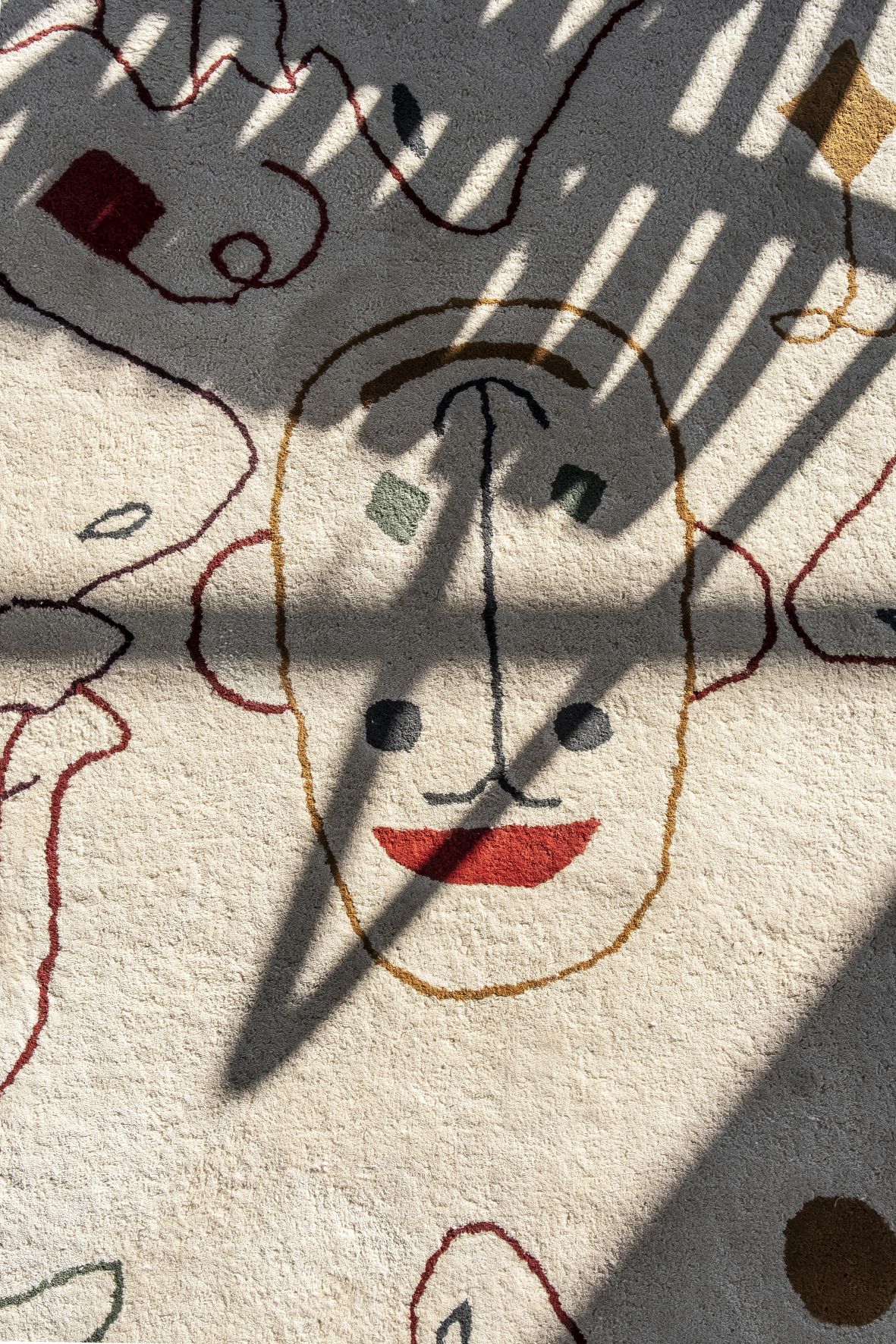 Detailaufnahme Nanimarquina Teppich: Beige Outdoor Teppich mit abstraktem Gesichtsmuster und Schatten.