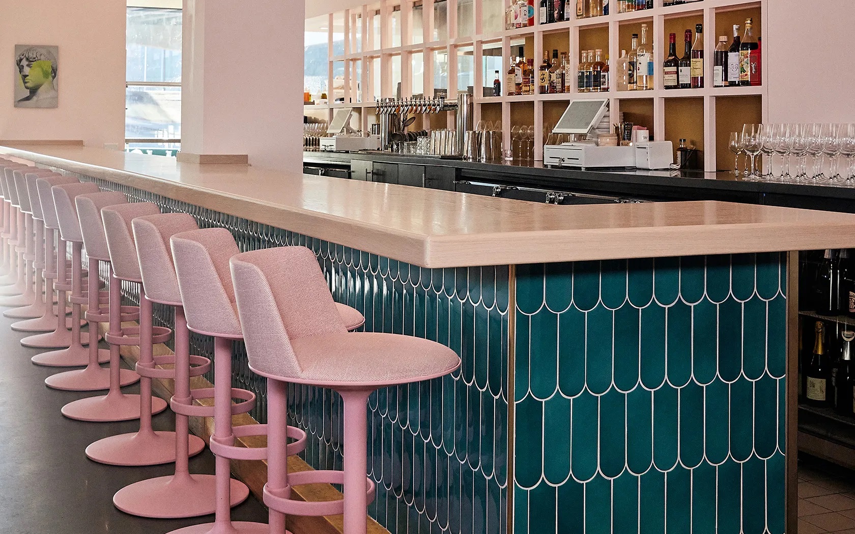 Reihe von Hula Barhockern von Andreu World in Rosa an einer Bar mit grünen Fliesen.